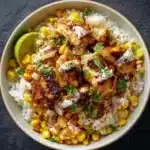 Street corn chicken rice bowl with colorful toppings and garnishes.