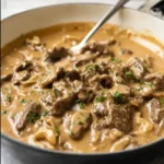 Close-up of creamy Gordon Ramsay Beef Stroganoff with tender beef strips, mushrooms, and rich sour cream sauce in a skillet