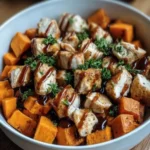 BBQ Chicken Sweet Potato Bowl with grilled chicken, sweet potatoes, and BBQ sauce topped with herbs in a white bowl